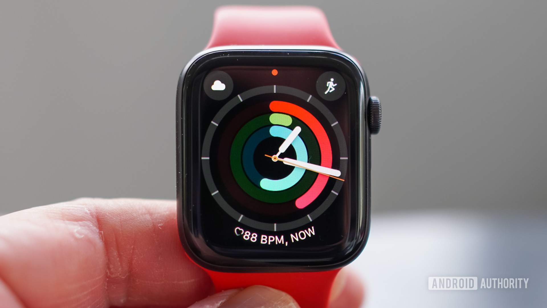 A user holds an Apple Watch SE display the activity rings watch face