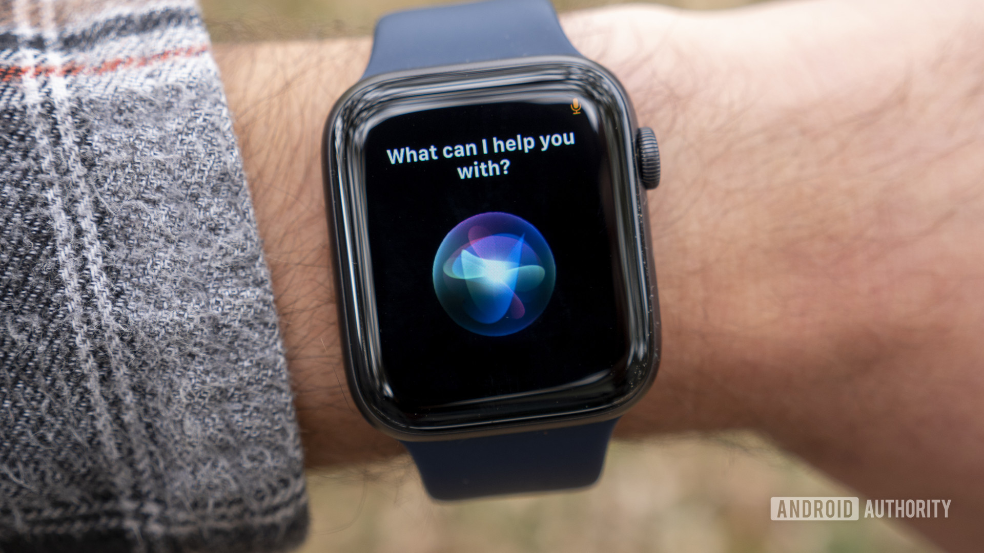 A user with a Space Gray Apple Watch Series 6 on his on wrist displays Siri voice assistant.