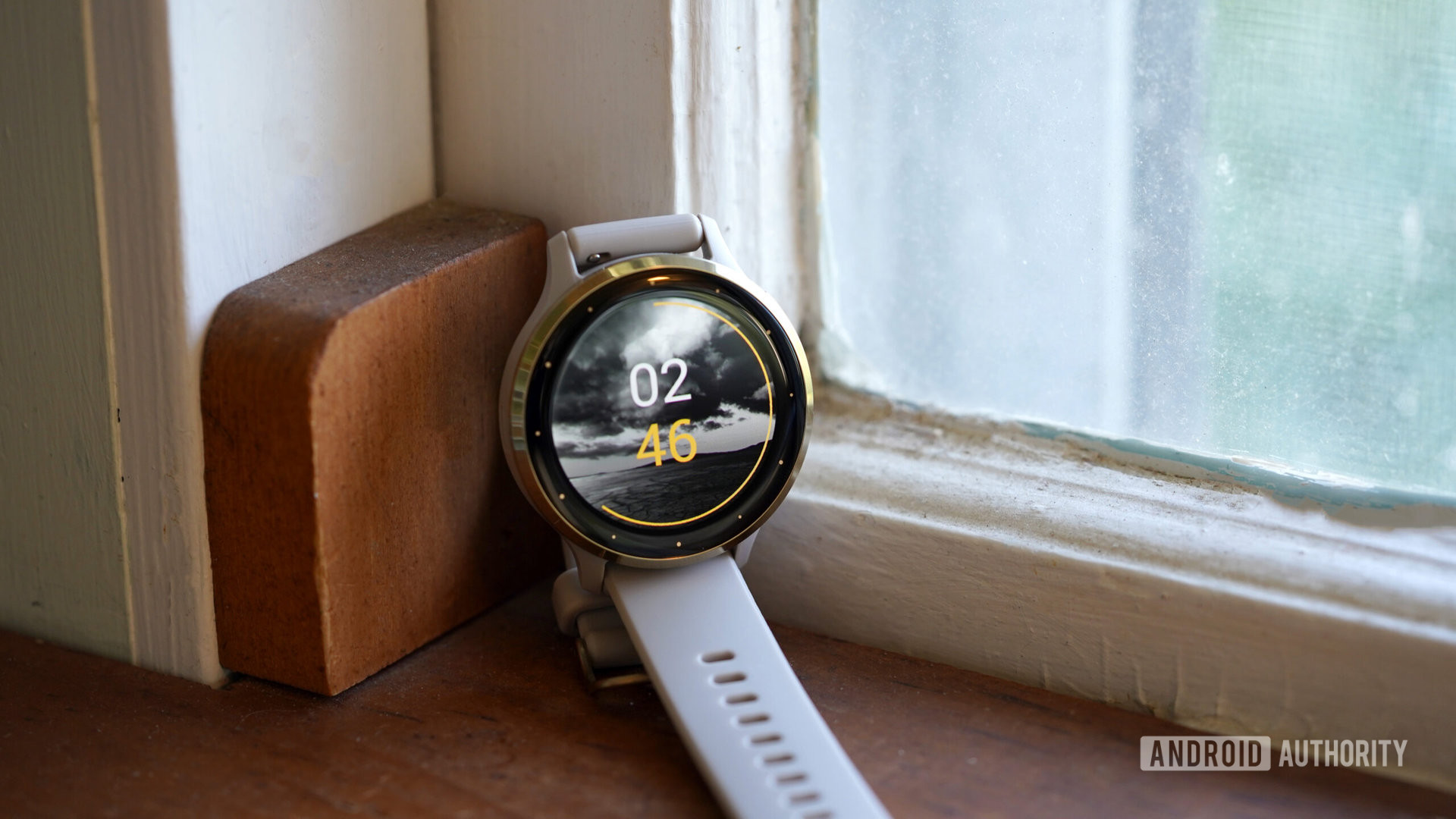 A Garmin Venu 3 rests in a window sill displaying a first-party watch face.