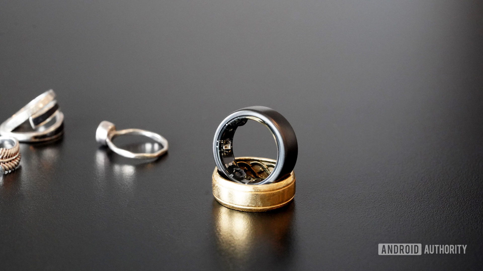 An Oura Ring 3 rests along side traditional jewelry.