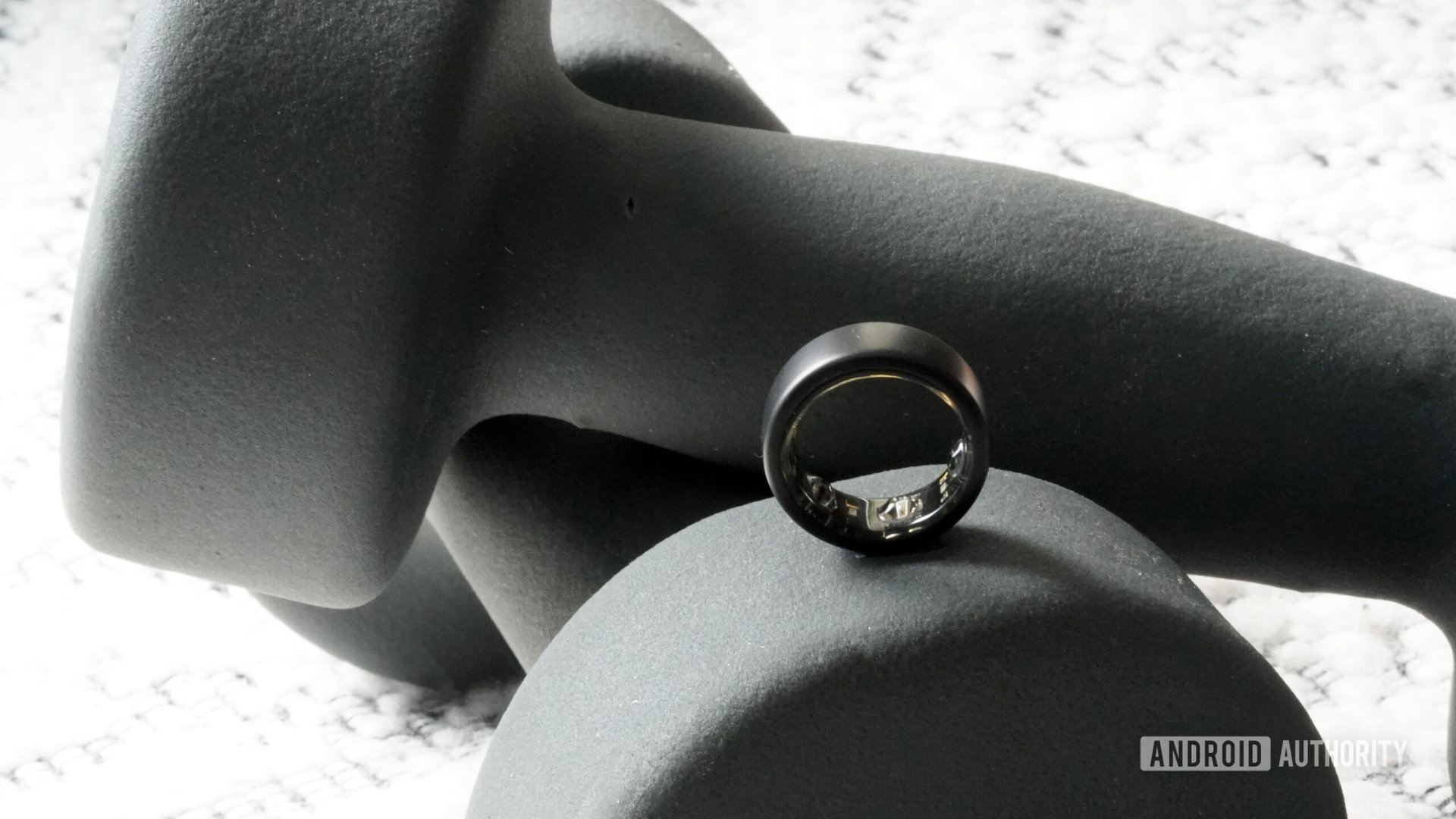 An Oura Ring 3 rests on a set of weights.